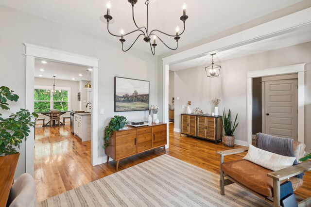 sitting room with baseboards, an inviting chandelier, and light wood-style floors
