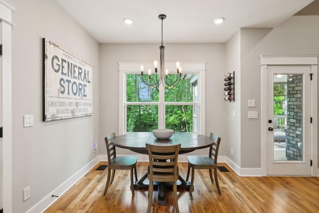 dining room with an inviting chandelier, baseboards, light wood-style flooring, and a wealth of natural light