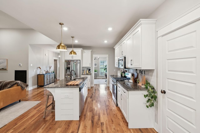 kitchen with a breakfast bar area, backsplash, appliances with stainless steel finishes, a sink, and white cabinetry