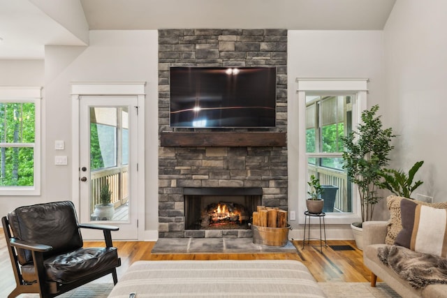 living area with baseboards, wood finished floors, and a fireplace