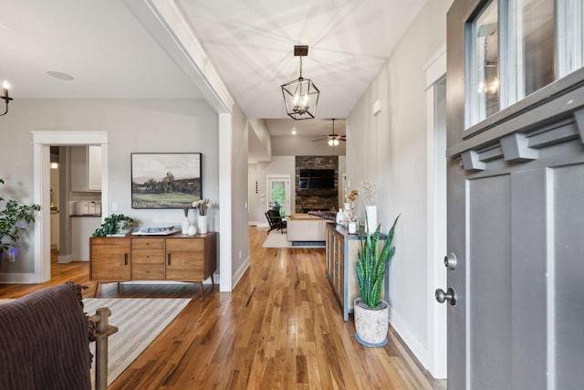 foyer featuring baseboards, ceiling fan with notable chandelier, and wood finished floors