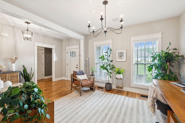 living area with an inviting chandelier, wood finished floors, and visible vents