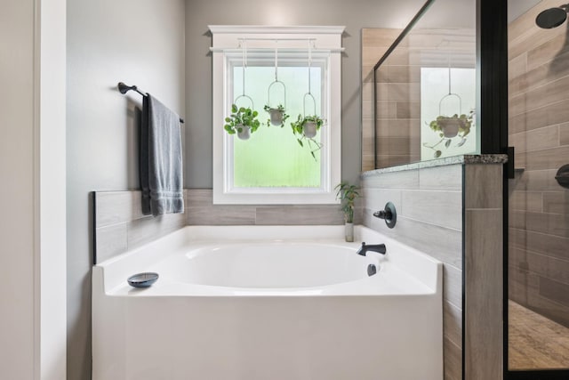 full bathroom with a bath, a wealth of natural light, and a shower stall