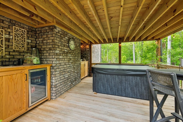 wooden terrace featuring beverage cooler and a hot tub