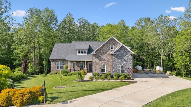 craftsman house featuring a wooded view, concrete driveway, a front lawn, and stone siding