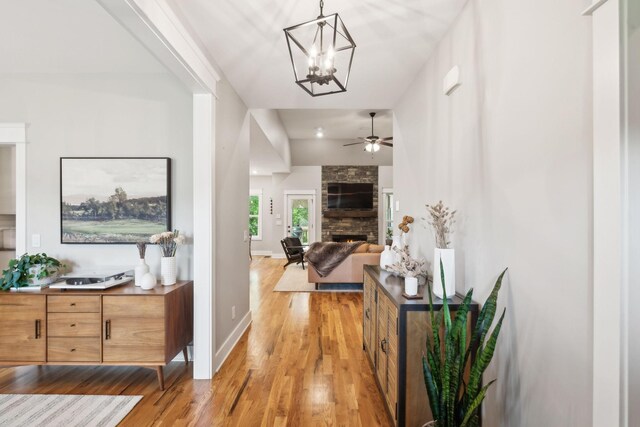 corridor with baseboards, light wood-style flooring, and a chandelier