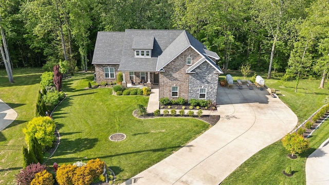view of front facade featuring a front yard, driveway, and stone siding