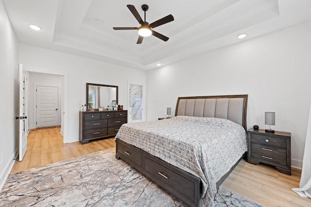 bedroom featuring recessed lighting, a raised ceiling, and light wood-type flooring