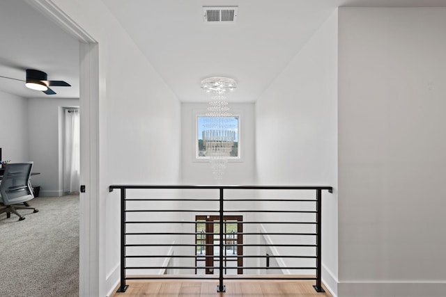 hall with carpet flooring, baseboards, an inviting chandelier, and visible vents