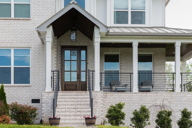 property entrance with covered porch, brick siding, a standing seam roof, and metal roof