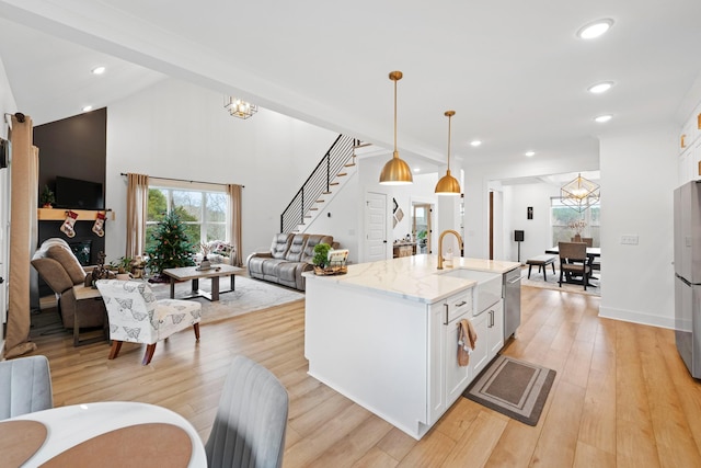 kitchen featuring plenty of natural light, a sink, open floor plan, an inviting chandelier, and stainless steel appliances