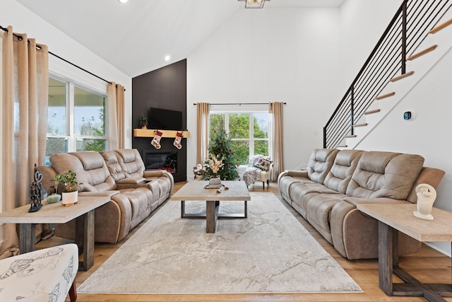 living room with stairway, high vaulted ceiling, recessed lighting, and light wood finished floors