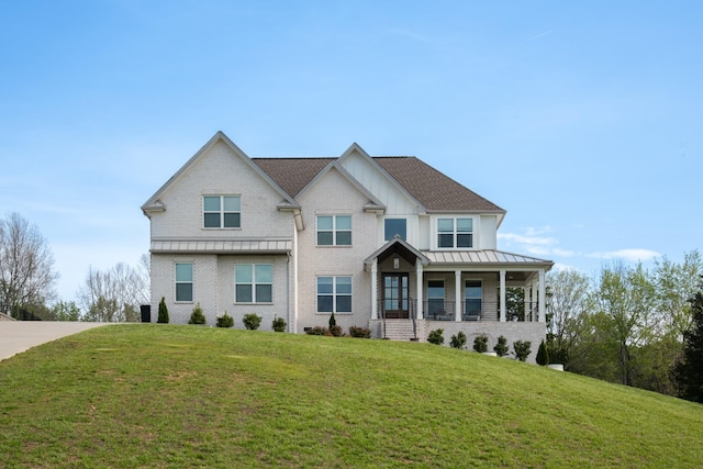 view of front of house featuring a porch, board and batten siding, a standing seam roof, brick siding, and a front lawn