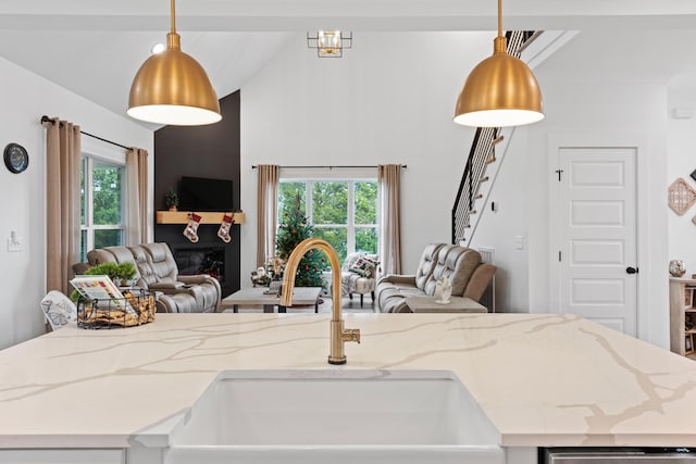 kitchen with open floor plan, light stone countertops, a sink, and high vaulted ceiling