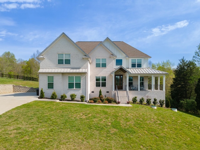 view of front of home with a front lawn, covered porch, a standing seam roof, brick siding, and metal roof