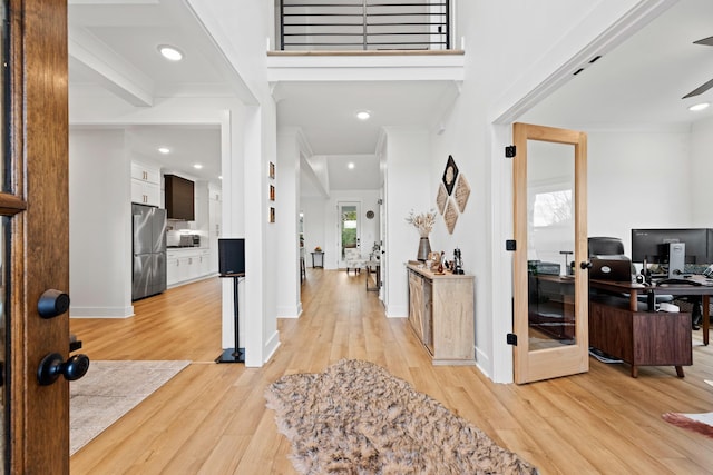 entrance foyer with light wood-type flooring, baseboards, crown molding, and a healthy amount of sunlight