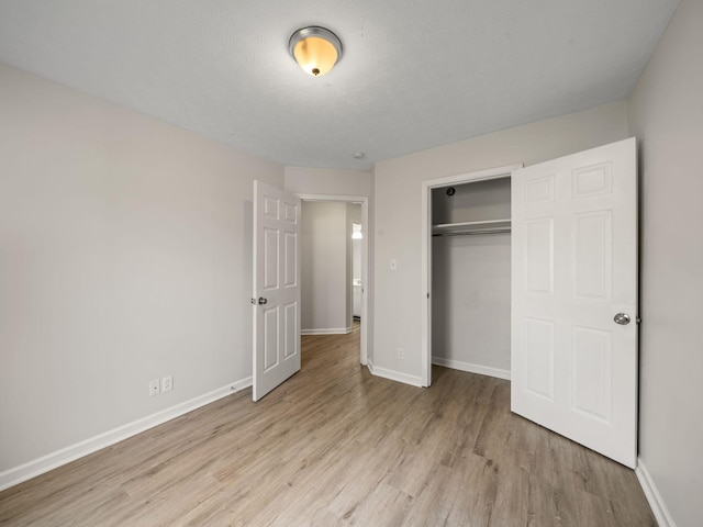 unfurnished bedroom featuring baseboards, wood finished floors, and a closet