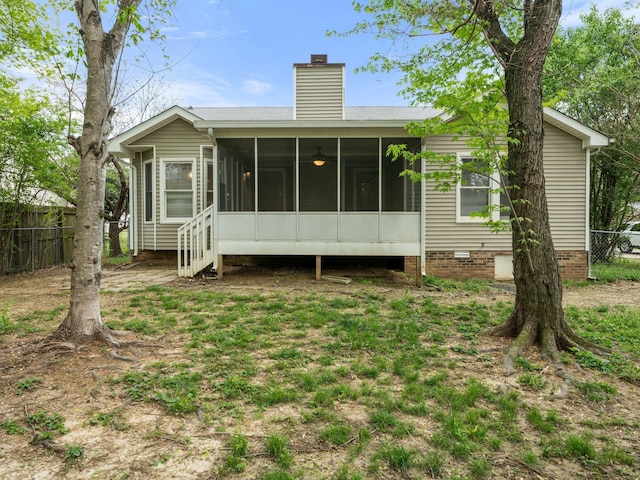 rear view of property featuring fence, a chimney, a sunroom, and crawl space