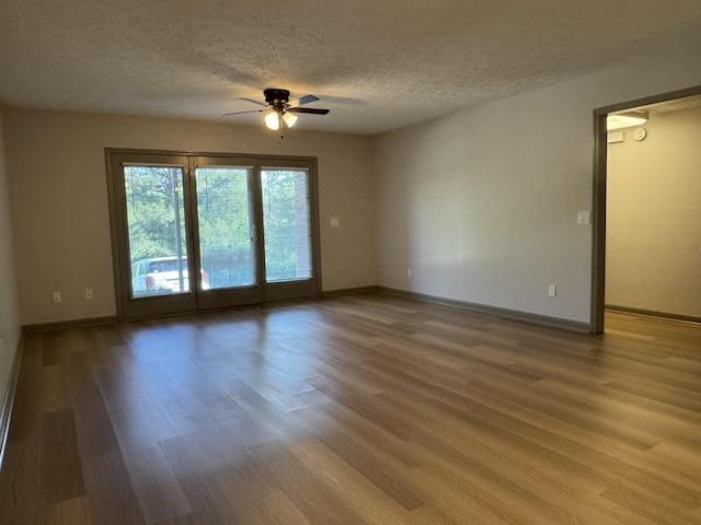 unfurnished room with baseboards, a ceiling fan, light wood-type flooring, and a textured ceiling