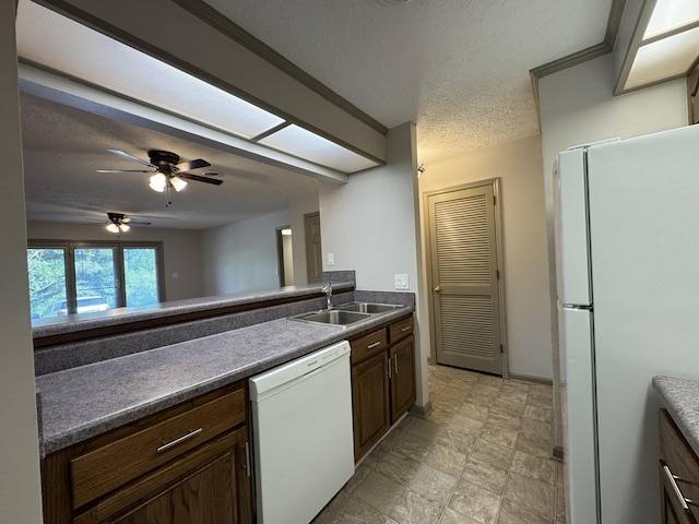 kitchen featuring ceiling fan, a textured ceiling, dark countertops, a sink, and white appliances