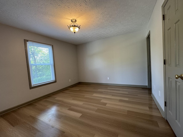 empty room with baseboards, a textured ceiling, and light wood-style flooring