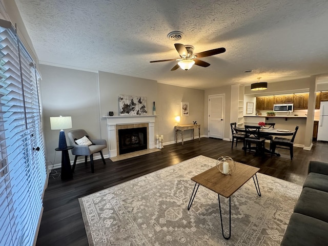 317 Village Ln W, Dickson, TN 37055 - living area featuring a textured ceiling, a tiled fireplace, a ceiling fan, baseboards, and dark wood-style floors