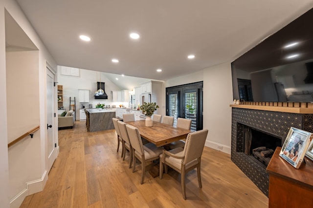 2025 Sanford Dr, Mount Juliet, TN 37122 - dining room featuring a tiled fireplace, recessed lighting, light wood-style flooring, and vaulted ceiling