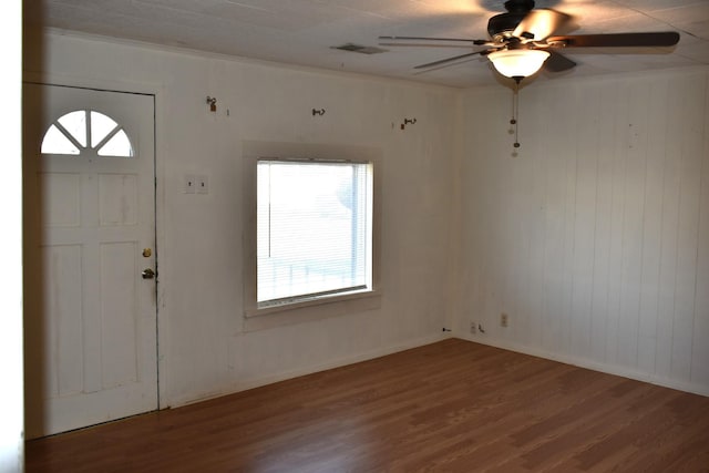 foyer with crown molding, ceiling fan, baseboards, wood finished floors, and visible vents