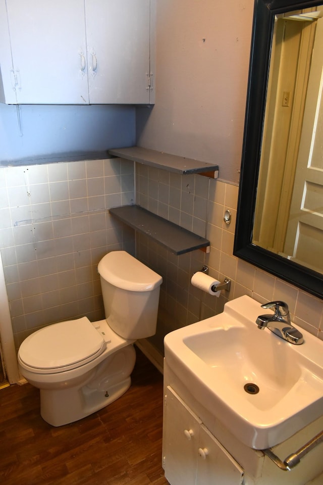 half bathroom with vanity, toilet, tile walls, decorative backsplash, and wood finished floors