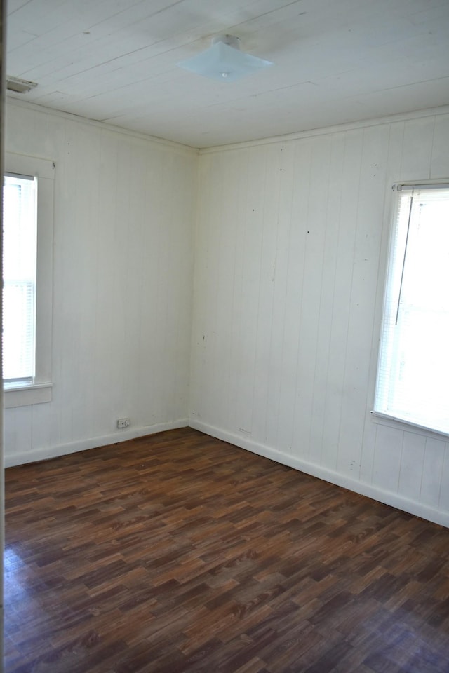 unfurnished room featuring wood walls, ceiling fan, a healthy amount of sunlight, and dark wood-style floors