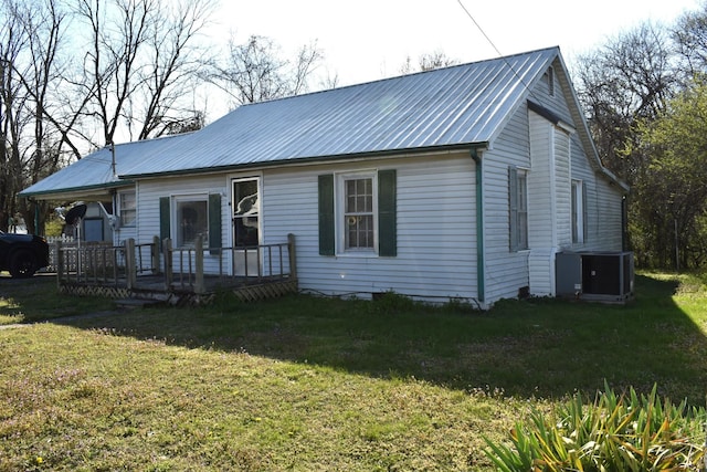 rear view of house with metal roof, a yard, and a deck