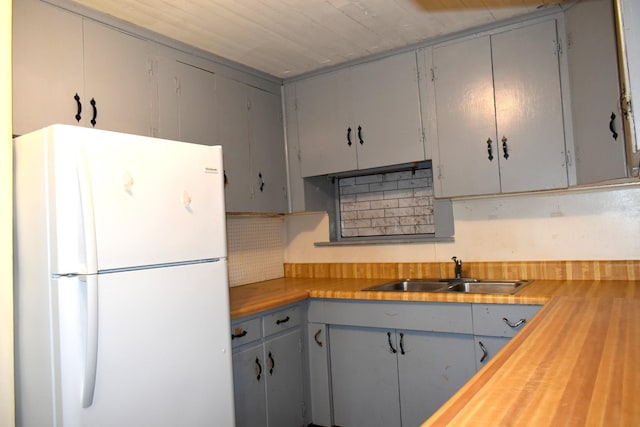 kitchen with a sink, freestanding refrigerator, and butcher block countertops