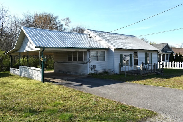 view of front of property with fence, metal roof, driveway, and a front lawn