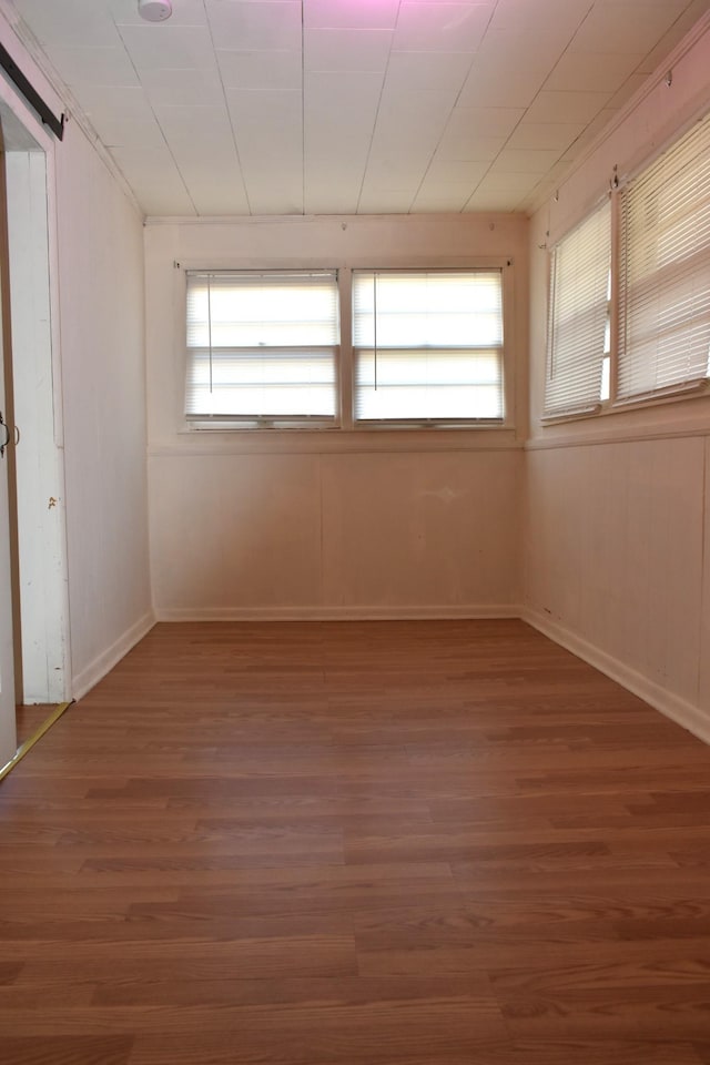 unfurnished bedroom with baseboards, multiple windows, and wood finished floors
