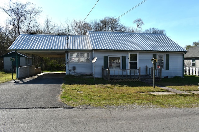 view of front of property featuring an attached carport, a front lawn, metal roof, and aphalt driveway