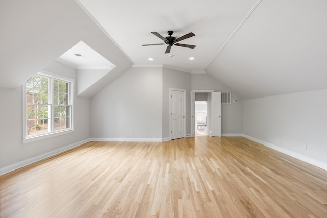 additional living space with baseboards, a ceiling fan, light wood-style flooring, and vaulted ceiling