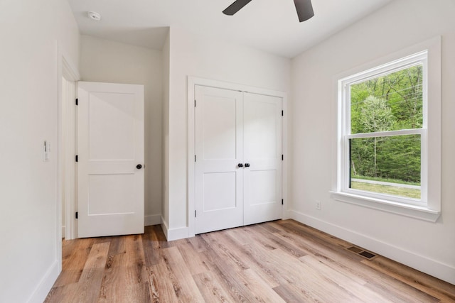 unfurnished bedroom featuring baseboards, visible vents, light wood finished floors, and a closet