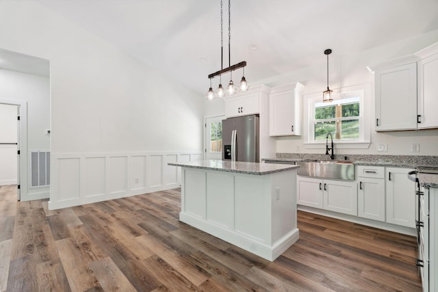 kitchen with white cabinets, stainless steel fridge, a sink, and a wealth of natural light