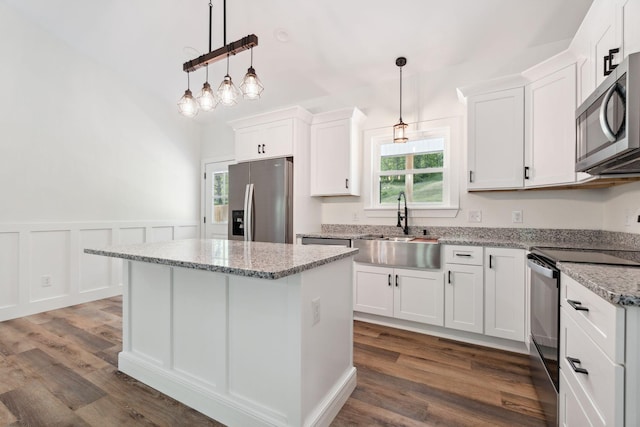 kitchen with a center island, dark wood finished floors, a sink, white cabinets, and stainless steel appliances