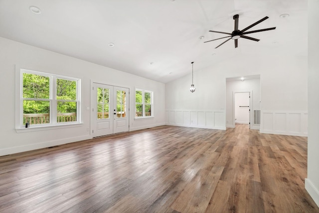 unfurnished living room featuring wood finished floors, a decorative wall, ceiling fan, high vaulted ceiling, and a wainscoted wall