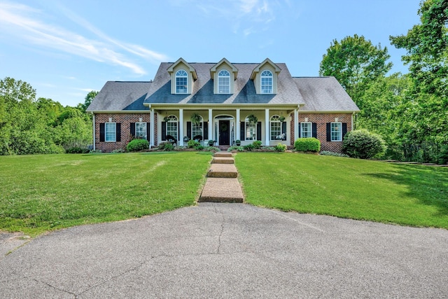 cape cod-style house with brick siding, a front lawn, and covered porch