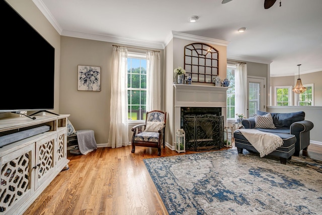 living room with baseboards, ornamental molding, a fireplace, and light wood-style flooring