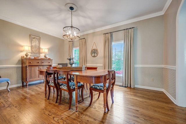 dining space featuring crown molding, plenty of natural light, wood finished floors, and a chandelier
