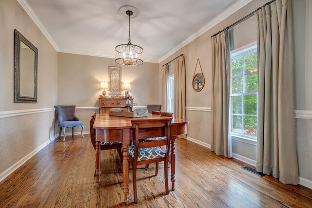 dining room featuring baseboards, ornamental molding, wood finished floors, and a notable chandelier