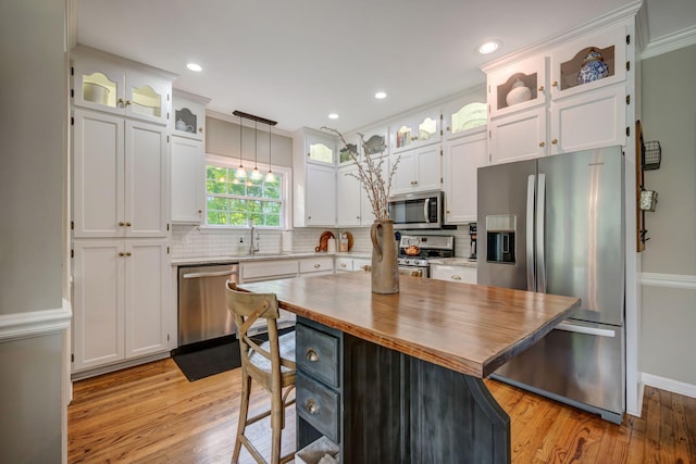 kitchen featuring backsplash, white cabinetry, light wood finished floors, stainless steel appliances, and butcher block countertops