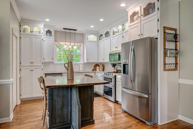 kitchen with light wood-style floors, decorative backsplash, stainless steel appliances, and white cabinetry