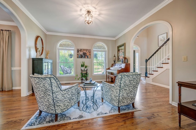 sitting room with arched walkways, ornamental molding, and wood finished floors