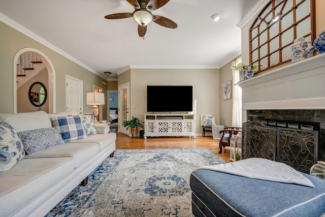 living area with a ceiling fan, ornamental molding, wood finished floors, and a fireplace