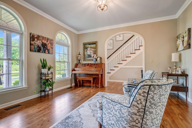 sitting room with crown molding, baseboards, wood finished floors, visible vents, and stairway
