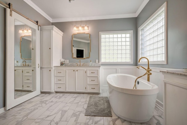 full bathroom with ornamental molding, marble finish floor, a freestanding bath, and two vanities